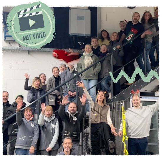 KI generiert: Eine Gruppe von Menschen posiert lächelnd auf einer Treppe, und das Bild enthält dekorative grafische Elemente wie eine Filmklappe und Früchte. Die Atmosphäre wirkt fröhlich und gemeinschaftlich.