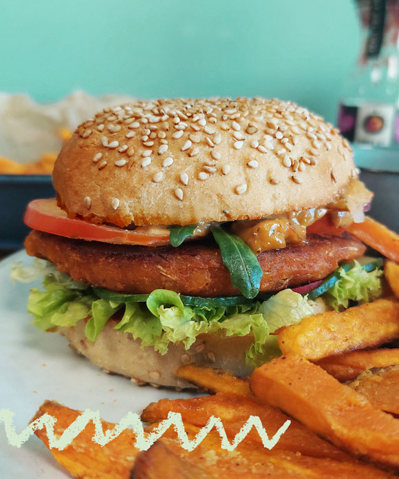 KI generiert: Ein Burger mit Sesambrötchen, Gemüse und Pommes Frites.