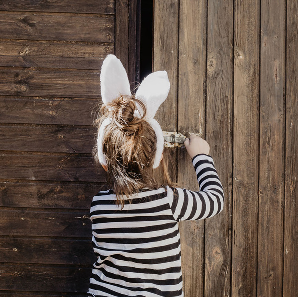 KI generiert: Ein Kind mit Hasenohren öffnet eine Holztür.