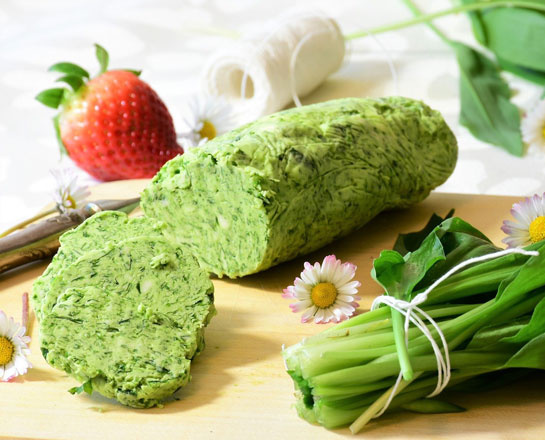 KI generiert: Kräuterbutter auf einem Brett mit Erdbeere und grünen Blättern.