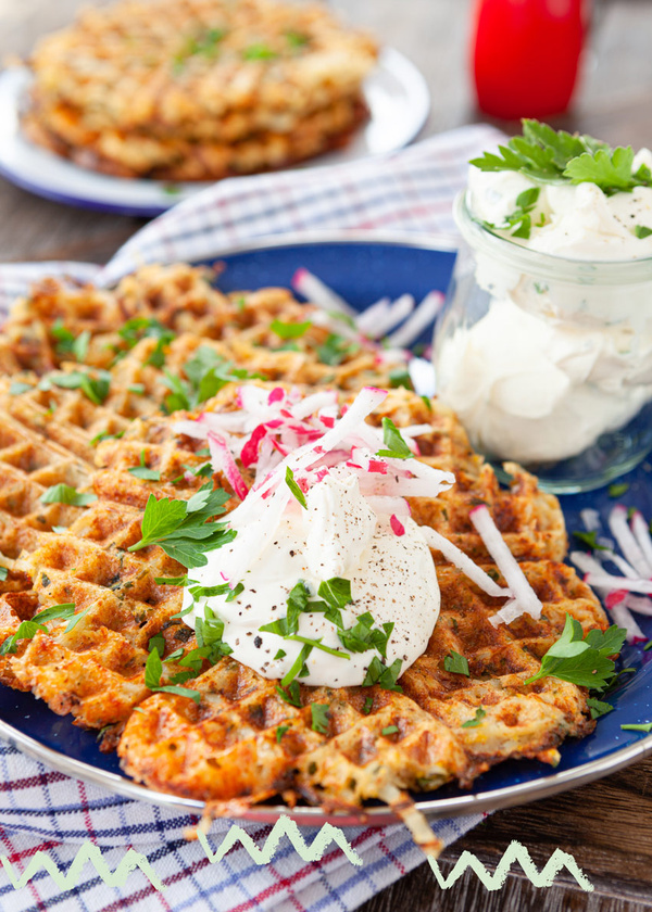 KI generiert: Herzhafte Waffeln mit saurer Sahne und Kräutern auf einem Teller, daneben ein Glas mit Sahne.