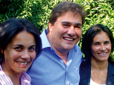 KI generiert: Ich weiß nicht, wer auf dem Bild ist. Drei Personen lächeln in die Kamera, Hintergrund ist grüne Vegetation.