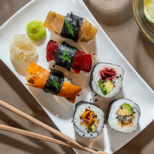 KI generiert: Ein Teller mit verschiedenen Arten von vegetarischem Sushi, dazu Wasabi und Ingwer.
