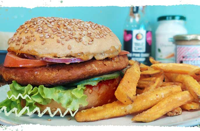 KI generiert: Ein Burger mit Pommes liegt auf einem Teller, im Hintergrund sind Gewürze.