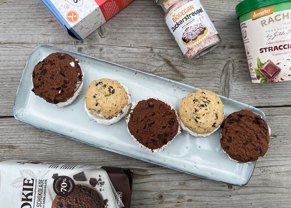 KI generiert: Drei Eis-Sandwiches auf einem Tablett, umgeben von Eis- und Keksverpackungen auf Holztisch.