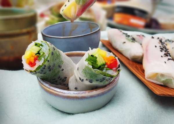 KI generiert: Bunte Sommerrollen mit Gemüse und Sesam in einer Schale, bereit zum Servieren.