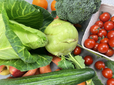 KI generiert: Das Bild zeigt eine Auswahl an frischem Gemüse und Obst, darunter Wirsing, Brokkoli, Kirschtomaten, Karotten, Kohlrabi, Gurke und Mandarinen. Der Hauptinhalt ist die Vielfalt an gesunden und farbenfrohen Lebensmitteln.