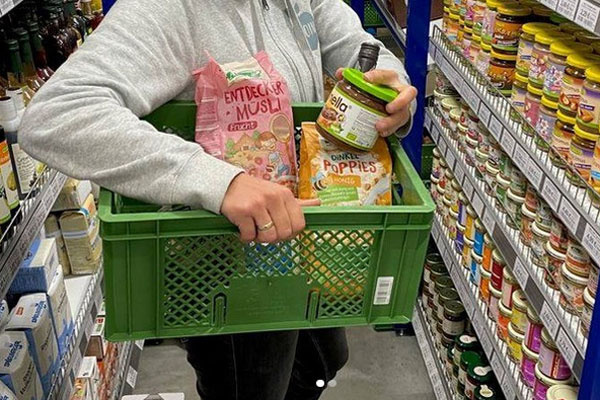 Person hält eine grüne Kiste mit Lebensmitteln.