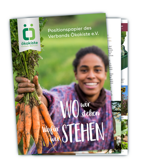 KI generiert: Eine Person hält frische Karotten. Text: "Positionspapier des Verbands Ökokiste e.V. Wo wir stehen, wofür wir stehen."