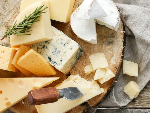 KI generiert: Verschiedene Käsesorten auf einem Holzbrett, mit einem Käsemesser und Rosmarin.