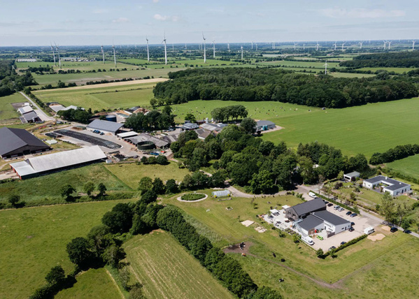 KI generiert: Luftaufnahme einer ländlichen Gegend mit Windrädern und Gebäuden.