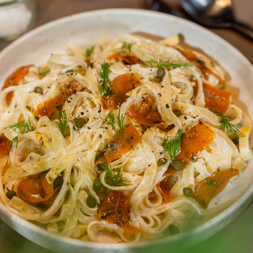KI generiert: Ein Teller Tagliatelle mit Sahnesoße, Karotten und frischen Kräutern.