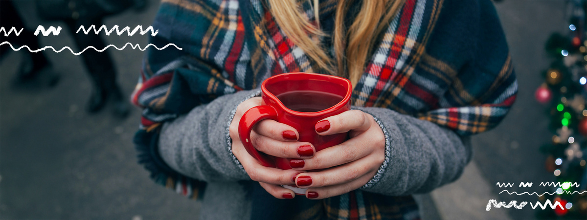 KI generiert: Eine Person hält eine rote Tasse mit Getränk, in warmen Kleidern.