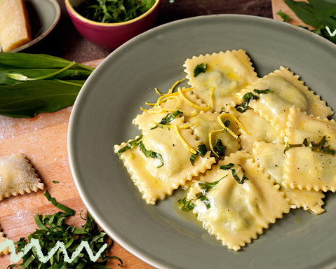 KI generiert: Ein Teller mit Ravioli, garniert mit Kräutern und Zitronenzesten, daneben frische Zutaten.