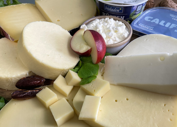 KI generiert: Verschiedene Käsesorten, aufgeschnittener Apfel und Datteln. Text: "bioladen", "CALIF".