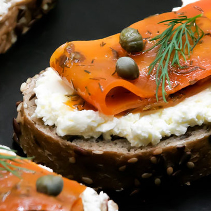 KI generiert: Ein belegtes Brot mit Frischkäse, Lachs, Kapern und Dill auf dunklem Körnerbrot.