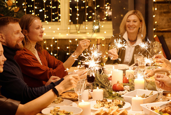 KI generiert: Eine festliche Gruppe mit Wunderkerzen am gedeckten Tisch.