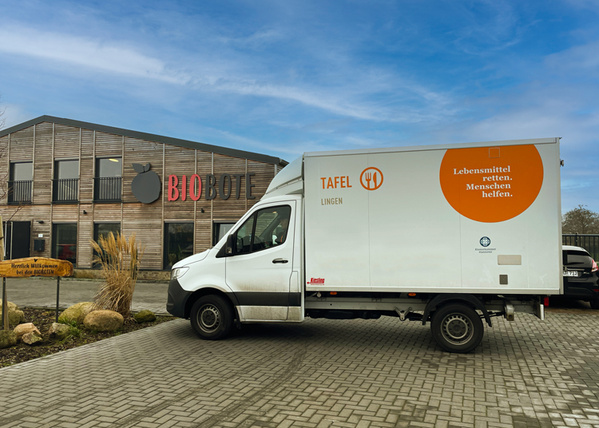 KI generiert: Ein Lieferwagen der Tafel vor dem Gebäude "BIOBOET". Text: "Lebensmittel retten. Menschen helfen."