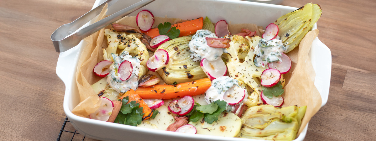 KI generiert: Bunte Ofengemüse-Mischung mit Kräuterdip in einer weißen Auflaufform.