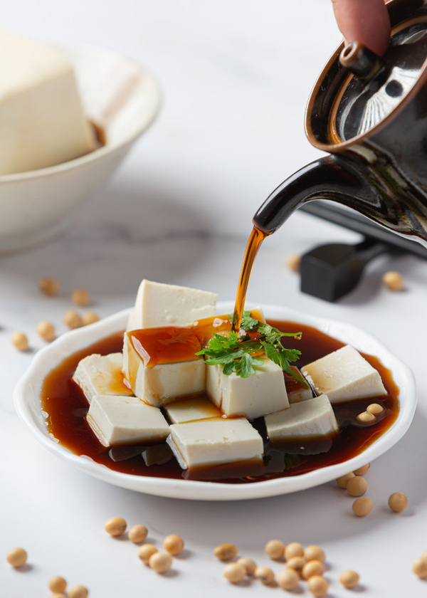 KI generiert: Tofu-Würfel auf einem Teller mit Sojasauce, garniert mit Koriander.