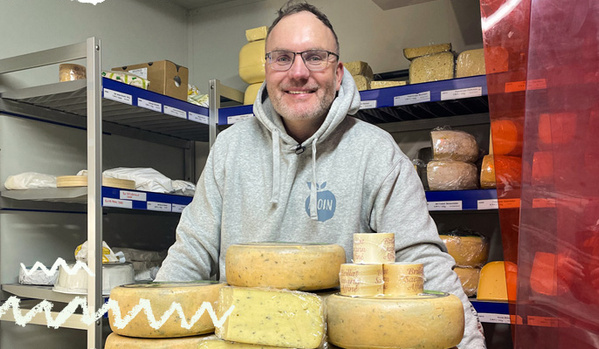 KI generiert: Ein Mann in einem Lagerraum mit vielen Käselaiben.