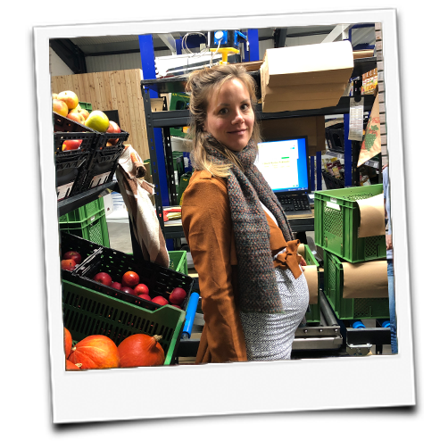 KI generiert: Eine Frau steht in einem Lager mit Kisten voller Obst.