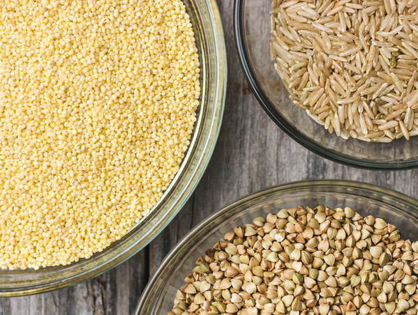 KI generiert: Drei Schalen mit Hirse, Reis und Buchweizen auf einem Holztisch.