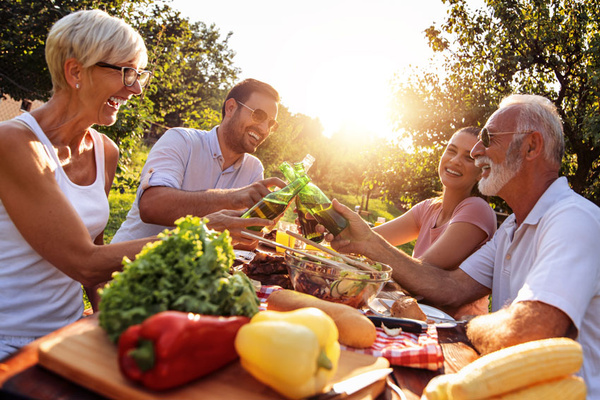 KI generiert: Eine Gruppe von Menschen genießt ein fröhliches Picknick im Freien mit Essen und Trinken.