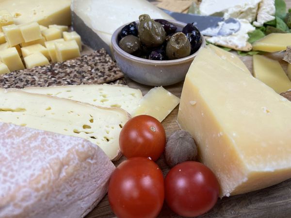 KI generiert: Käseplatte mit verschiedenen Käsesorten, Oliven, Crackern und Kirschtomaten.