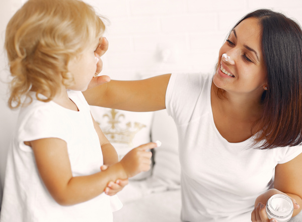 KI generiert: Eine Frau und ein Kind spielen lachend mit Gesichtscreme auf ihren Nasen.