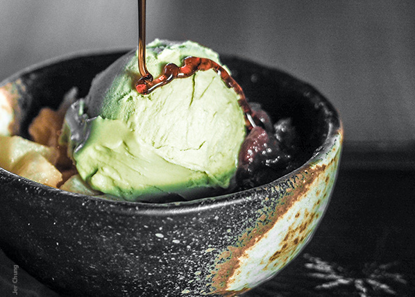 KI generiert: Grünes Eiscreme-Dessert in Schüssel mit Sirup und Beilagen.