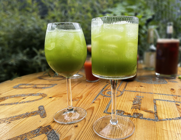 KI generiert: Das Bild zeigt gefüllte Champignons auf einem Holzbrett, garniert mit Käse und Kräutern. Im Hintergrund sind Zutaten wie Knoblauch, Nüsse und Öl zu sehen.