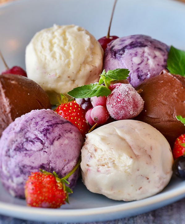 KI generiert: Verschiedene Eiskugeln mit Erdbeeren und Beeren auf einem Teller.