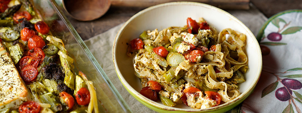 KI generiert: Eine Schüssel Pasta mit Gemüse und Feta neben einer Auflaufform mit ähnlichem Inhalt.