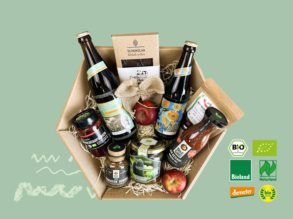 KI generiert: Ein Geschenkpaket mit Bio-Produkten: Getränke, Saucen, Schokolade. Enthält Logos von Bio-Zertifizierungen.