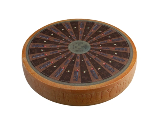 KI generiert: Ein runder Laib Le Gruyère Käse, Oberseite mit Etiketten versehen. Text: "Le Gruyère".