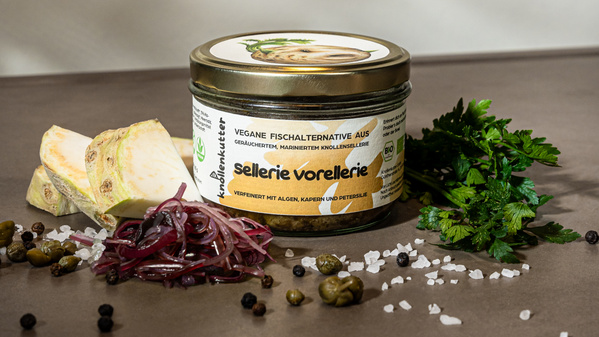 KI generiert: Ein Glas "Sellerie Vorellerie" mit Zutaten wie Sellerie, Kräutern und Gewürzen dekoriert. Text: "Vegane Fischalternative aus..."