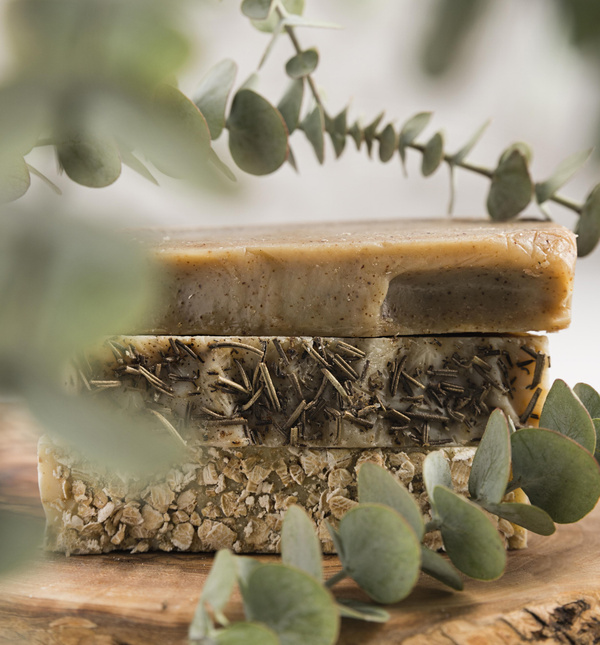 KI generiert: Zwei natürliche Seifenstücke liegen auf Holz, umgeben von Eukalyptusblättern.