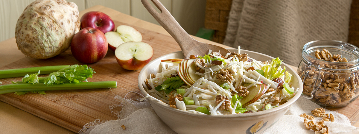 KI generiert: Ein Salat mit Äpfeln, Sellerie und Walnüssen auf einem Tisch mit frischen Zutaten.