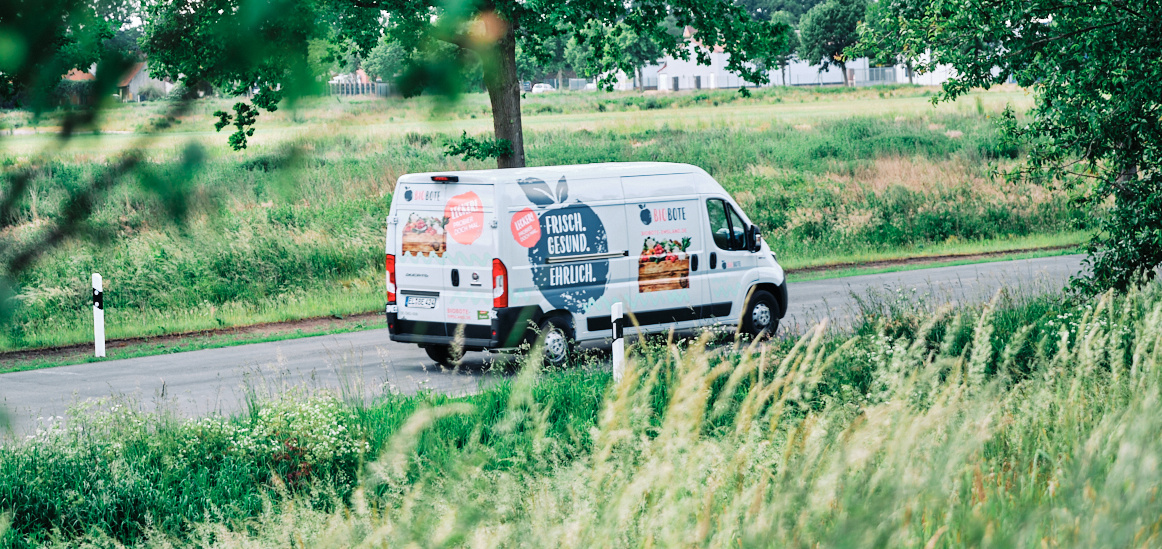KI generiert: Ein Lieferwagen fährt durch eine ländliche Gegend. Text: "FRISCH. GESUND. EHRLICH."