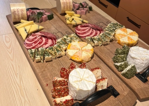 KI generiert: Holzbrett mit vielfältiger Auswahl an Käse und Wurst.