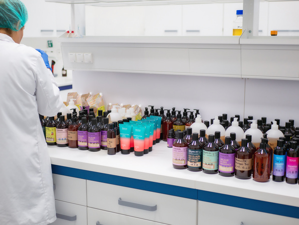 KI generiert: Eine Person in Laboruniform sortiert viele Flaschen und Tuben auf einem Tisch.