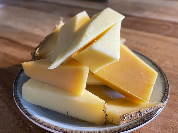 KI generiert: Mehrere Scheiben Käse auf einem kleinen Teller, auf einem Holztisch arrangiert.