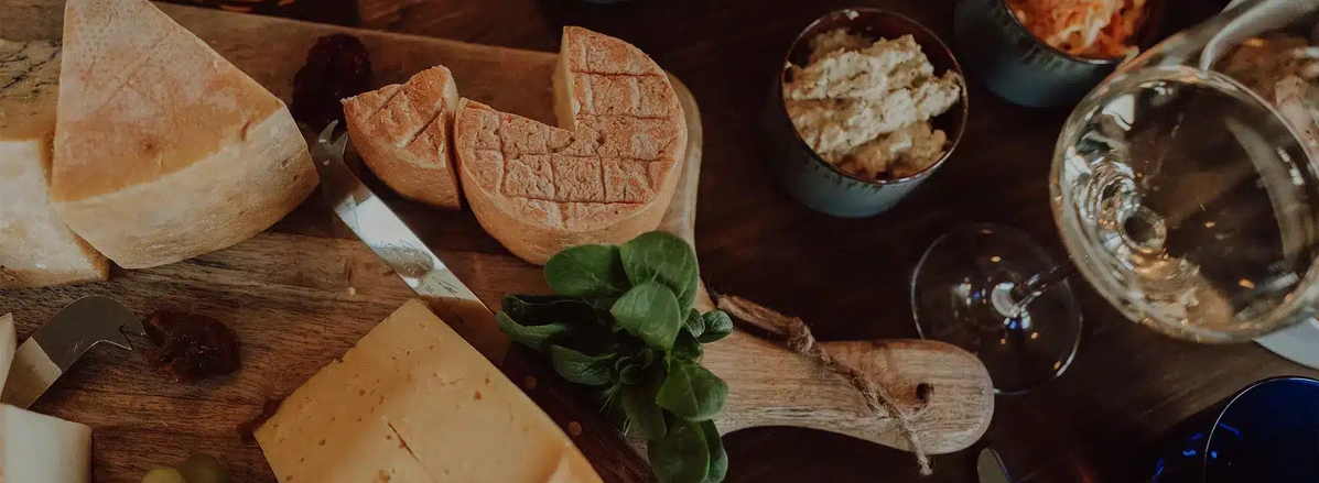 KI generiert: Käseplatte mit Brot, grünem Salat und einem Glas Weißwein.