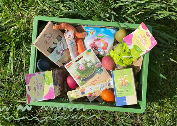 KI generiert: Ein grüner Korb mit Osterprodukten und Süßigkeiten, darunter bunte Eier und Verpackungen mit Ostermotiven.