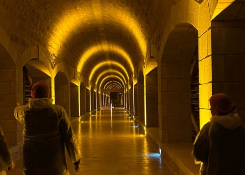 KI generiert: Ein stimmungsvoll beleuchteter, gewölbter Korridor mit zwei Personen in Schutzkleidung.